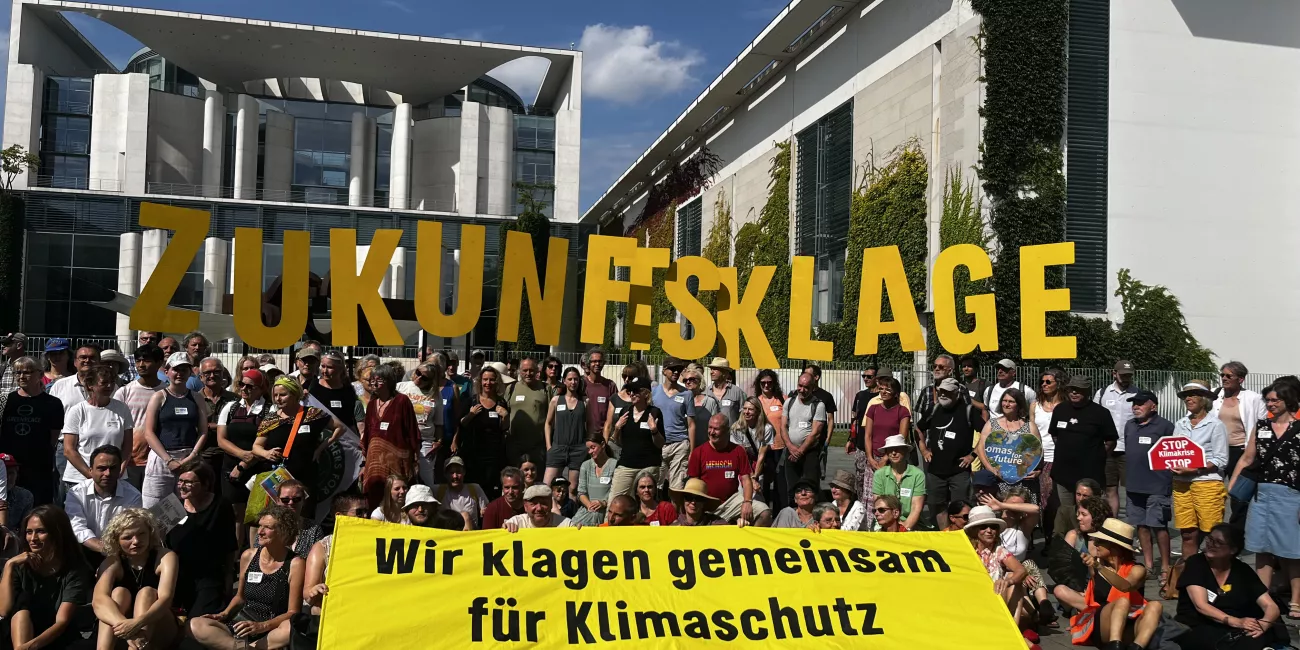 Viele Zukunfskläger:innen stehen vor dem Kanzleramt mit einem Banner, dass sagt: Wir klagen gemeinsam für Klimaschutz!