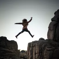 kleines Mädchen springt über große Felsen