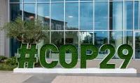 Schriftzug der COP29 in begrünten Lettern vor einer Fensterfront