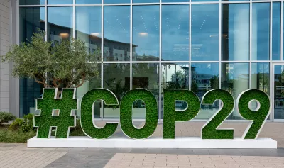 Schriftzug der COP29 in begrünten Lettern vor einer Fensterfront