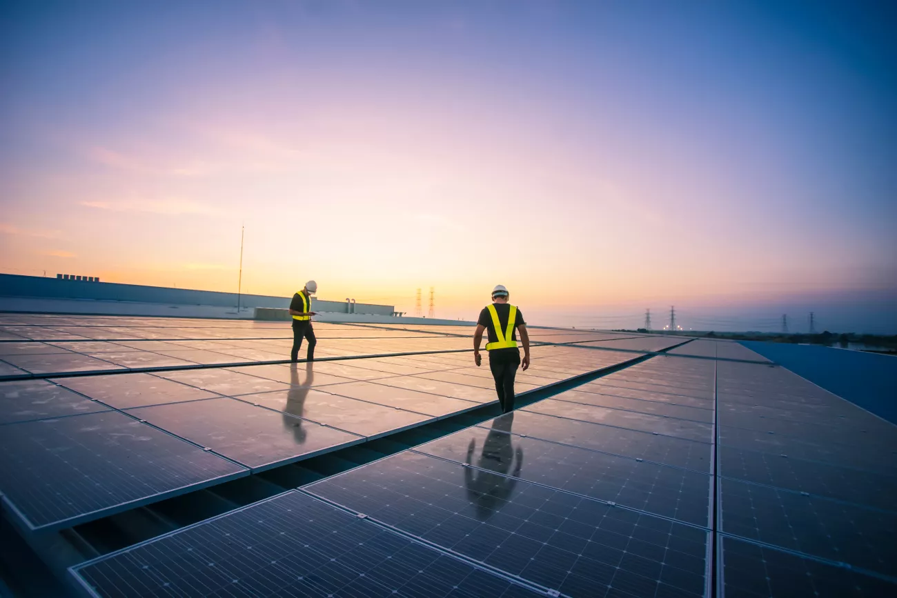 Arbeiter installieren Solarpanels auf einem Dach.