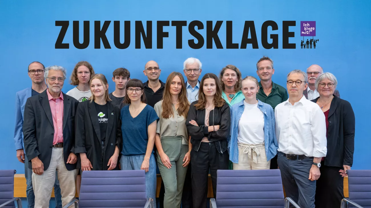 Titelbild Zukunftsklage - Gruppenfoto der Kläger:innen mit Schirftzug "Zukunftsklage"